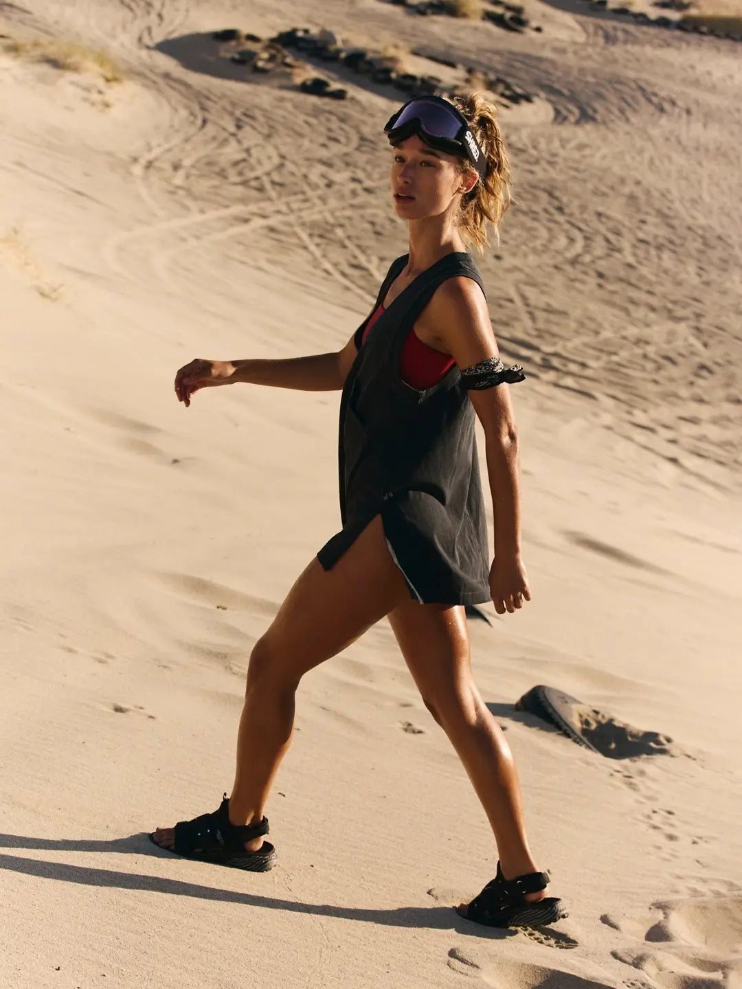 black sleeveless cotton cover-up dress with v neck wrap design worn over a red bikini top paired with black sandals