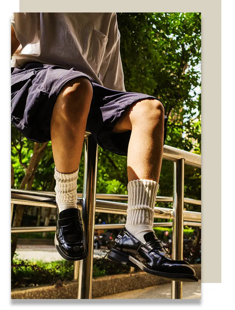 black patent leather loafers with a glossy finish and two-strap design complement vintage ribbed cotton long socks for men.