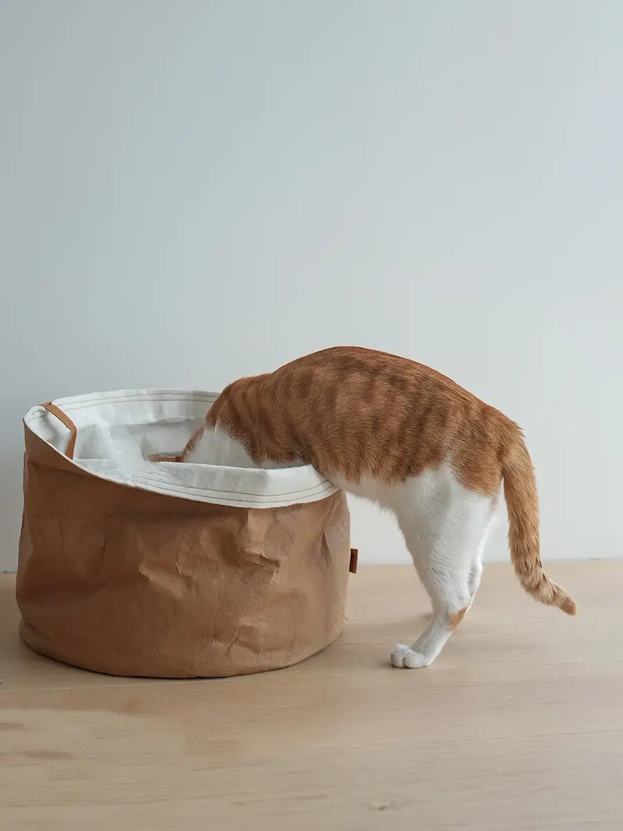 brown paper pet bed washable round dog cat nest with white interior lining tan fabric handles and durable kraft paper material.