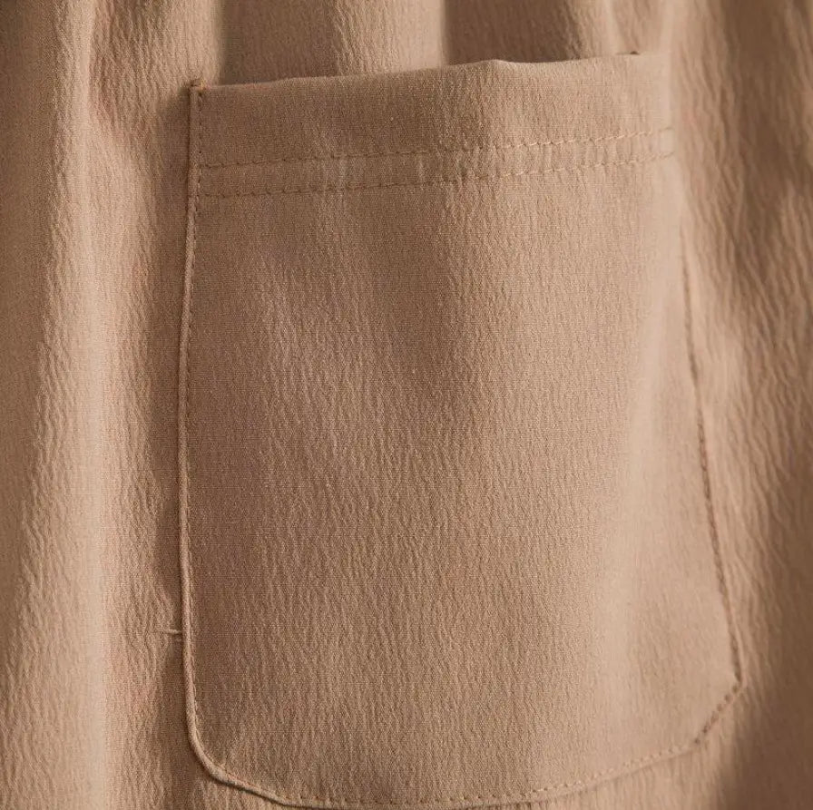 Poche en tissu beige, avec une texture subtile et une couture soignée sur le short de plage en coton lin pour hommes.