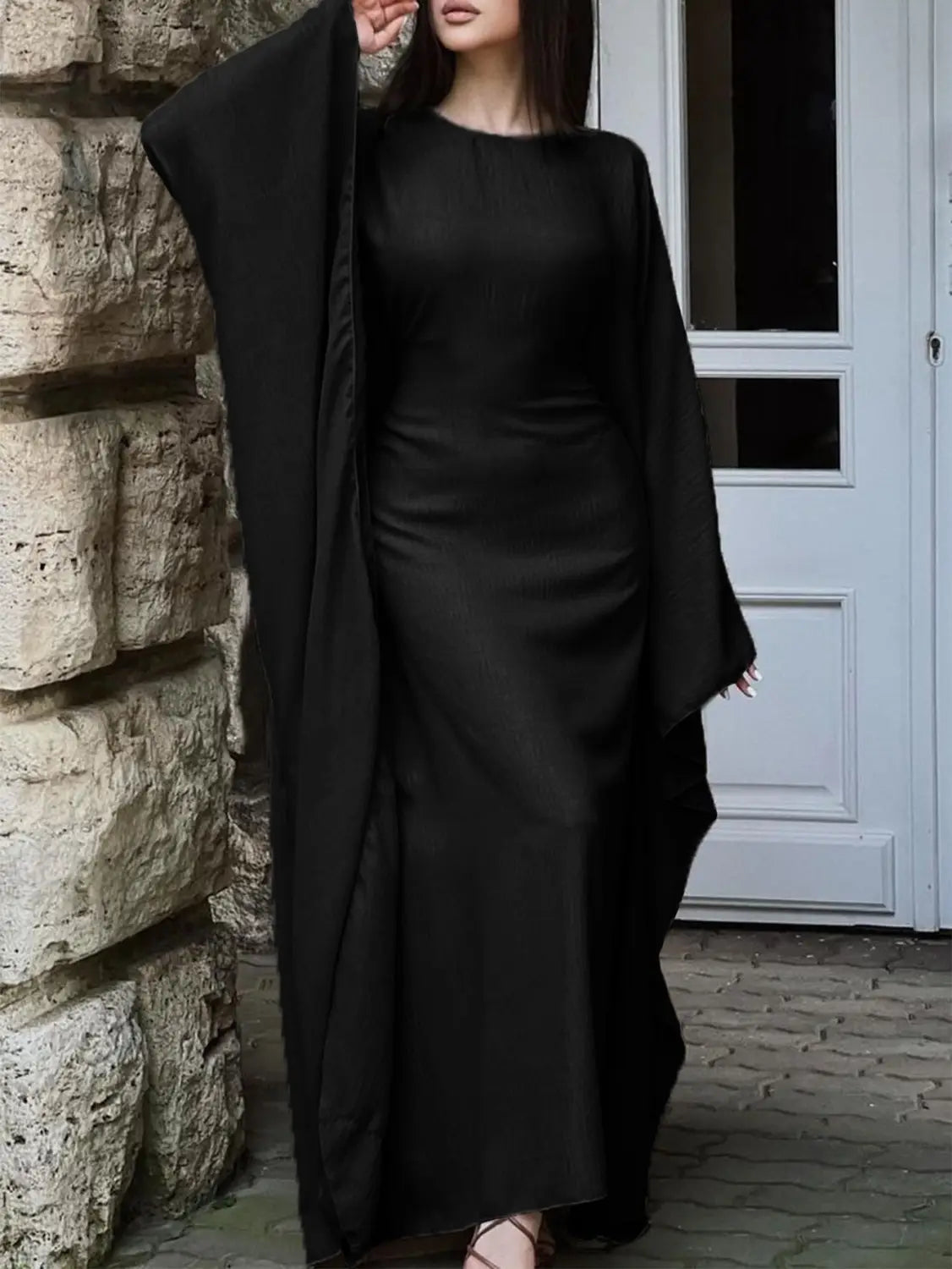 Black satin abaya with flowing wide sleeves and a sleek floor-length silhouette showcasing elegant long sleeve satin maxi dress with ruffled hem.