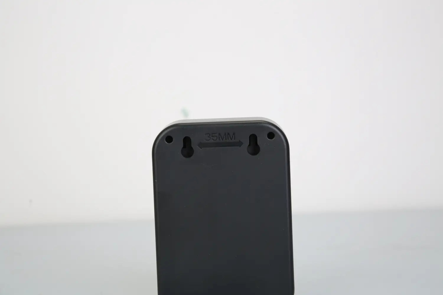 Black rectangular ultrasonic anti-barking device with rounded corners and three mounting holes on the back marked 35mm above a central slot, featuring IPX4 waterproof trainer functionality.
