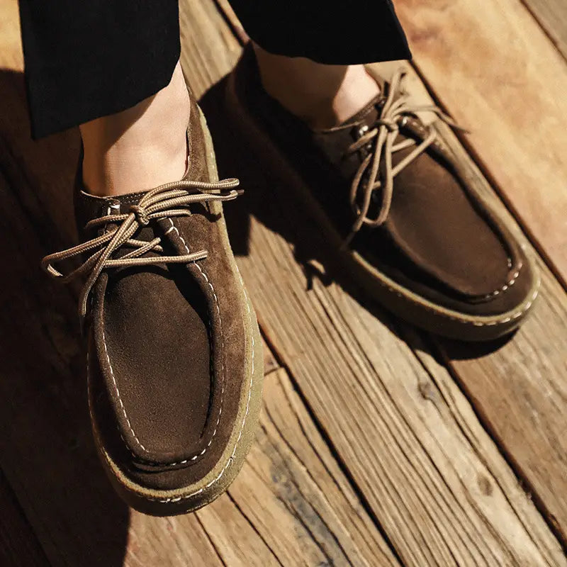Brown suede British style casual lace up leather shoes with tan laces and a thick slightly worn rubber sole.