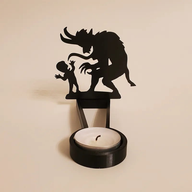 Black metal Halloween bat candle holder featuring a menacing creature and child silhouette with a circular base holding a white tea light for shadow decor.