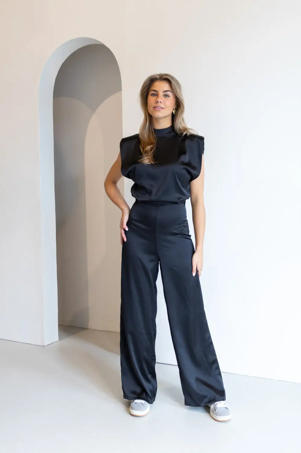 Black satin backless evening dress jumpsuit with puffy short sleeves and high-waisted wide-leg pants.