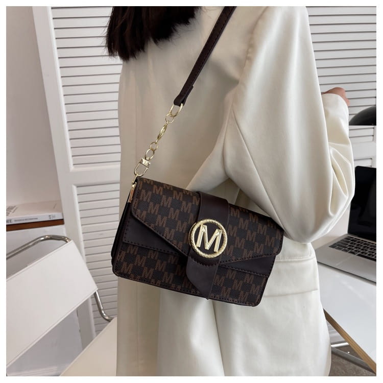 Black crossbody messenger bag with a repeating monogram pattern and gold-tone logo clasp for versatile daily use.