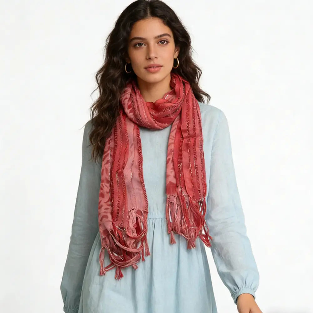 Un foulard en viscose rose poudré tacheté de léopard, doux, de couleur rose poudré, avec des fils métalliques, présentant un motif texturé discret et des bords à franges.