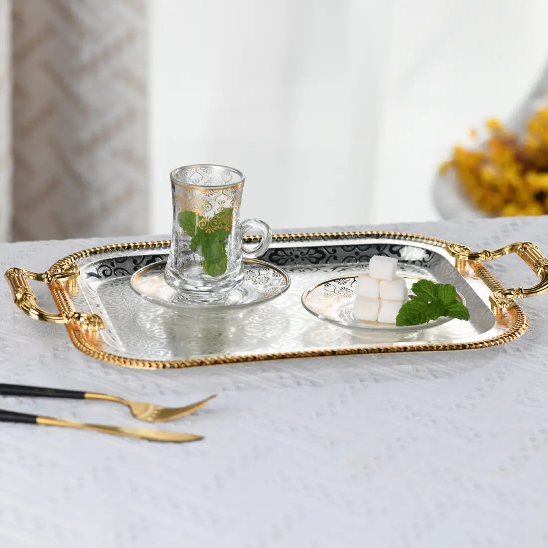 Luxury rectangle serving tray with ornate gold handles and a mirrored silver surface featuring intricate black filigree detailing along the edges.