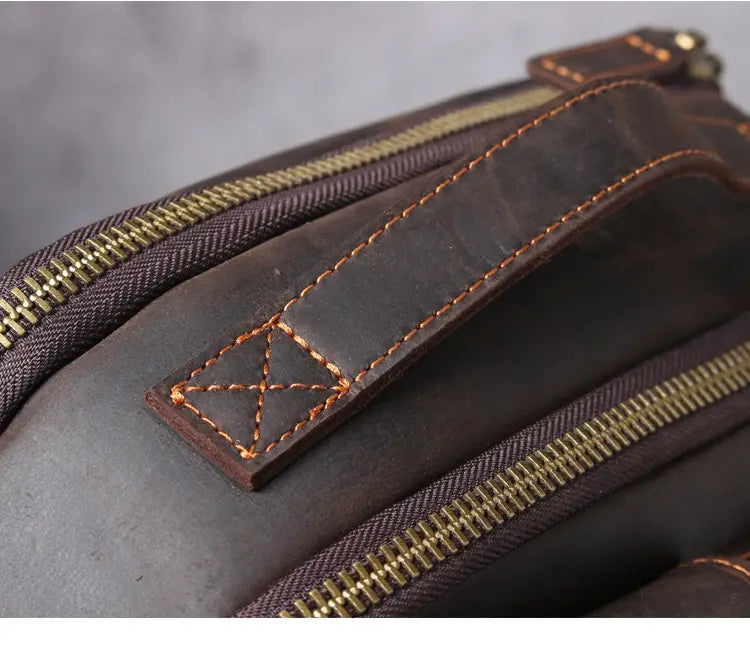 Men’s vintage leather backpack in dark brown cowhide featuring brass zippers and contrasting tan stitching.