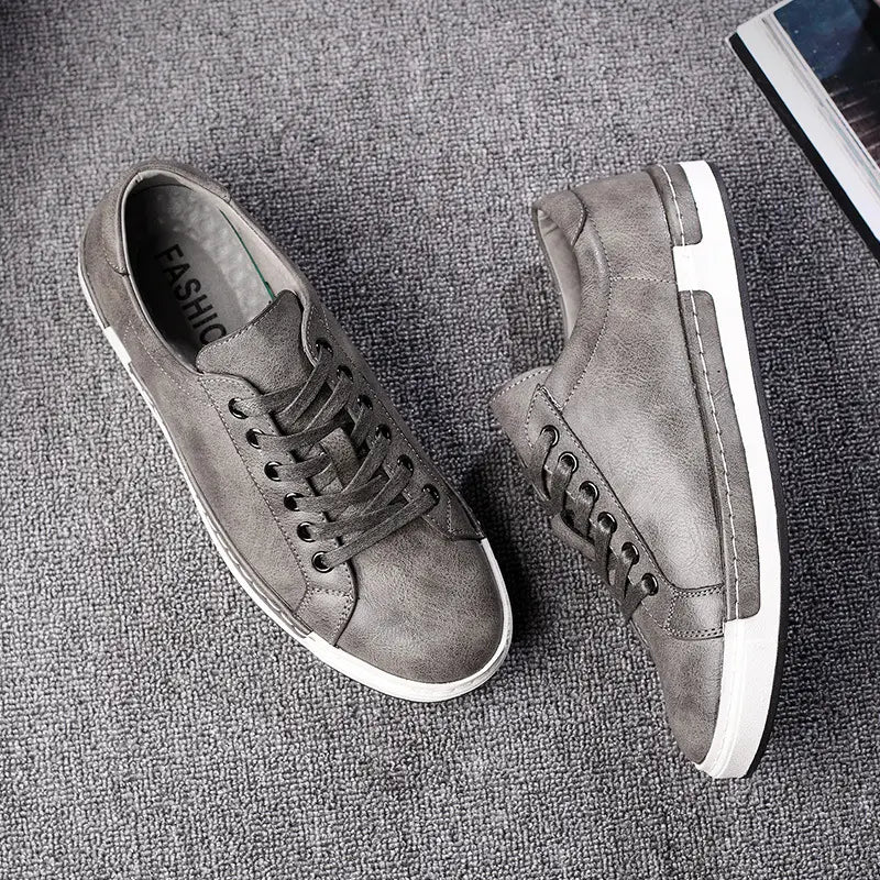 Les baskets basses en cuir pour homme, faites à la main, en daim gris, avec des semelles en caoutchouc blanc et des lacets assortis, pour un usage décontracté.