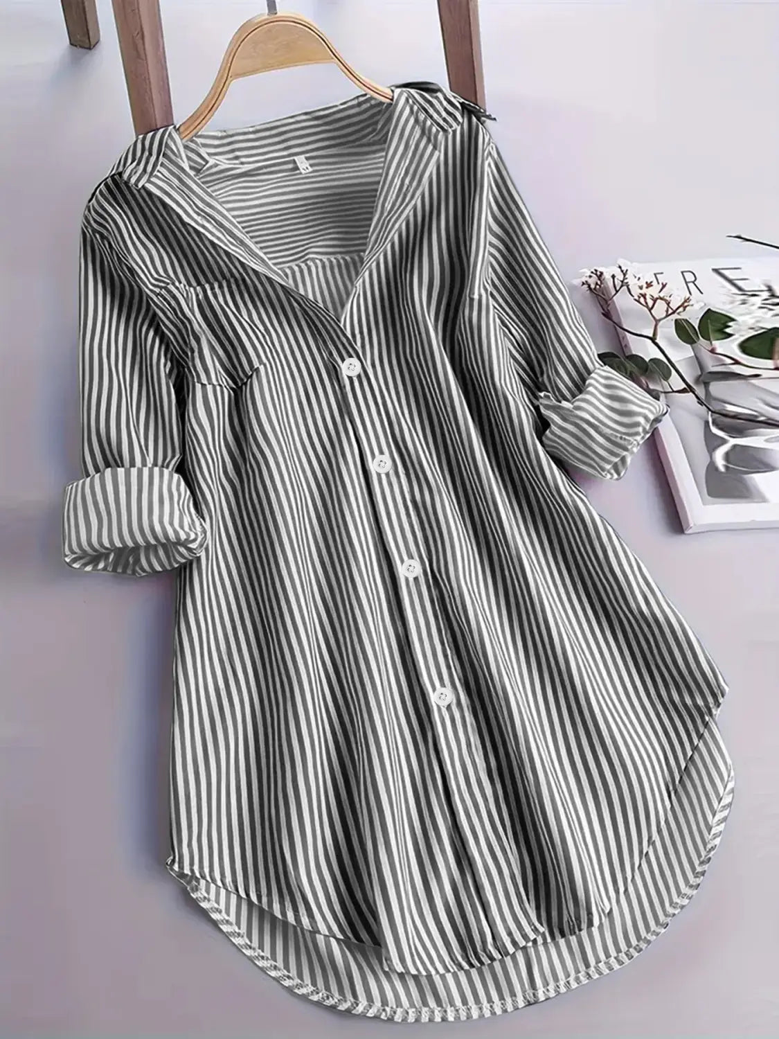 Chemise boutonnée à manches longues, ample et ajustement confortable, à rayures verticales noir et blanc, poignets retroussés et ourlet arrondi, adaptée à un usage décontracté.