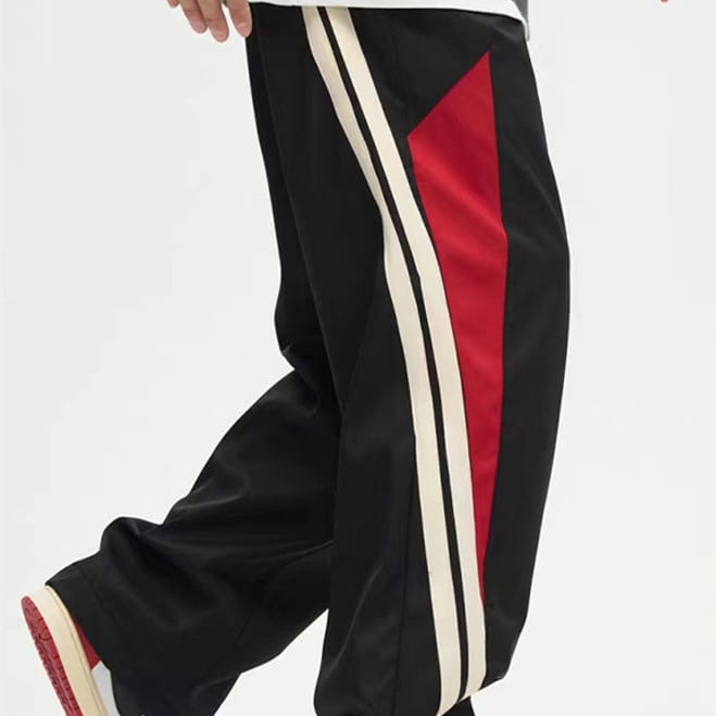 Men’s retro striped athletic track pants in black featuring bold red and white striped side panels suitable for casual and sportswear.