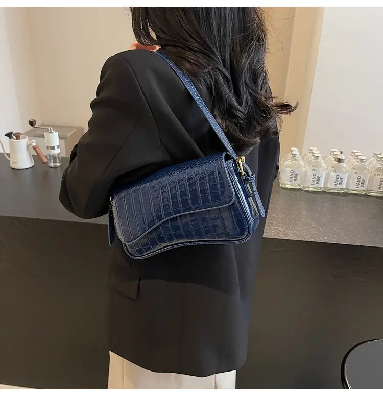 Deep blue crocodile-embossed leather messenger bag with a sleek structured design and gold-tone hardware ideal for minimalist crossbody use.