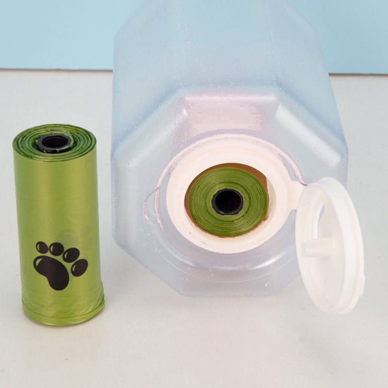 Un rouleau de sacs à déjections pour animaux en plastique vert brillant avec un motif d’empreintes de pattes noires inclus dans une gourde pour chien 3 en 1 avec sac à crottes.