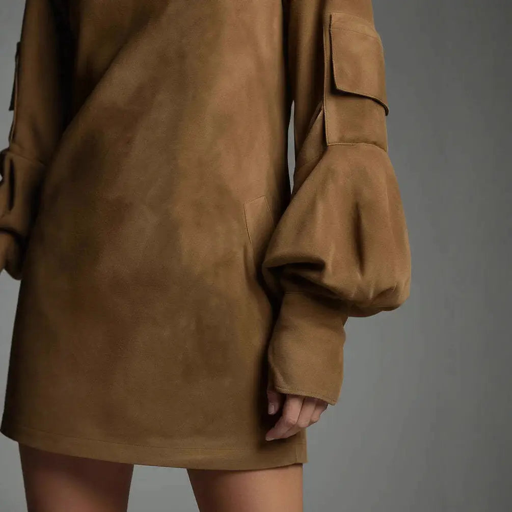 A tan suede mini dress with a turtleneck, voluminous bell sleeves, and patch pockets.