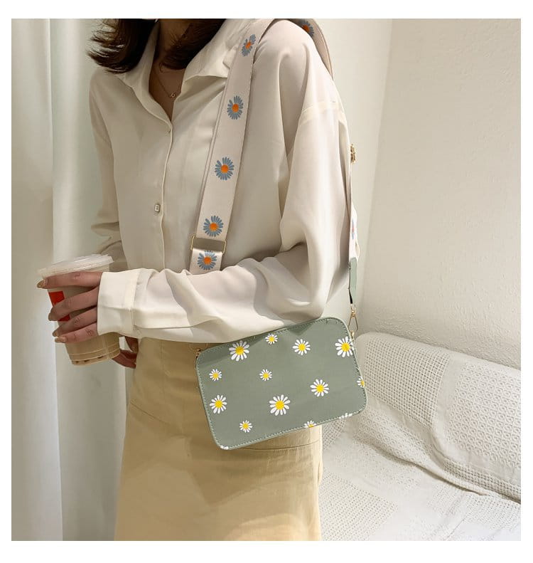 A light green pu leather crossbody bag with a chain strap featuring a pattern of white daisies with yellow centers called daisy flower crossbody bag chain strap pu leather.