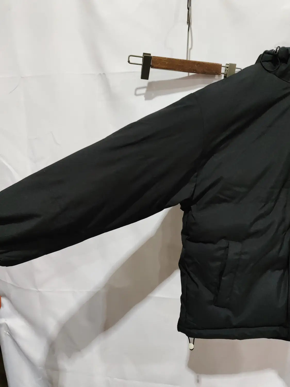 Damen-Kapuzensteppjacke mit wattierter Polsterung in Schwarz mit Stepp-Design und Kordelzug am Saum.