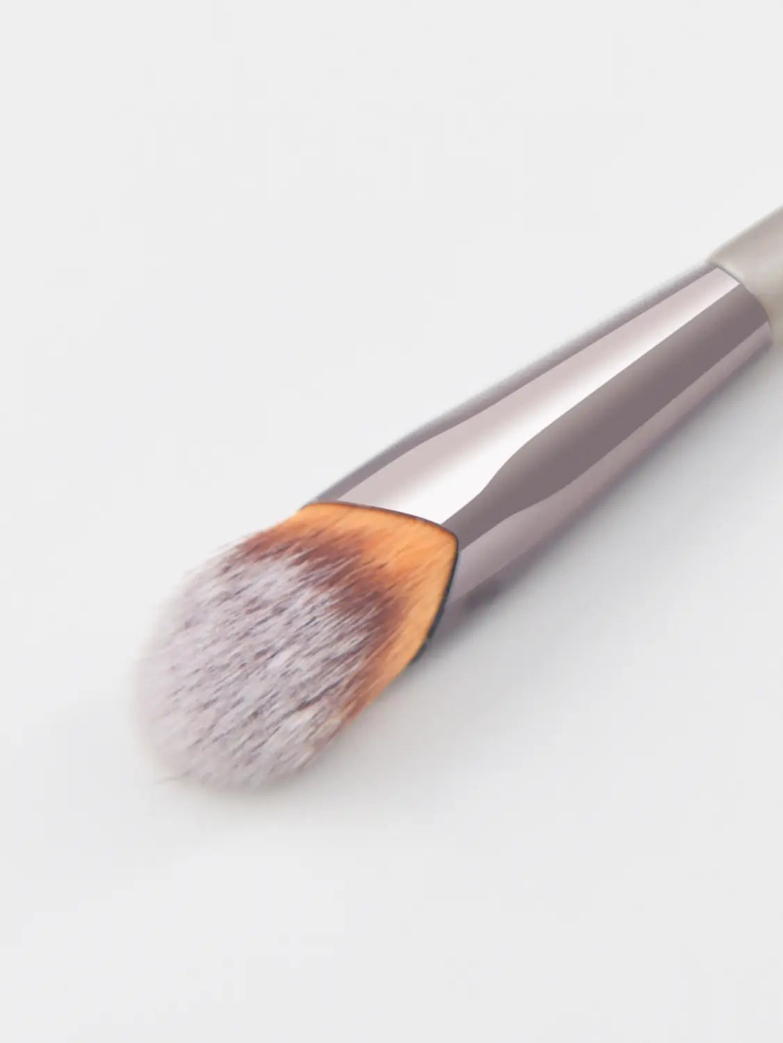 A sleek metallic-finish finger belly makeup brush with a dense soft bristle head transitioning from light gray to warm orange designed as a professional contour tool.
