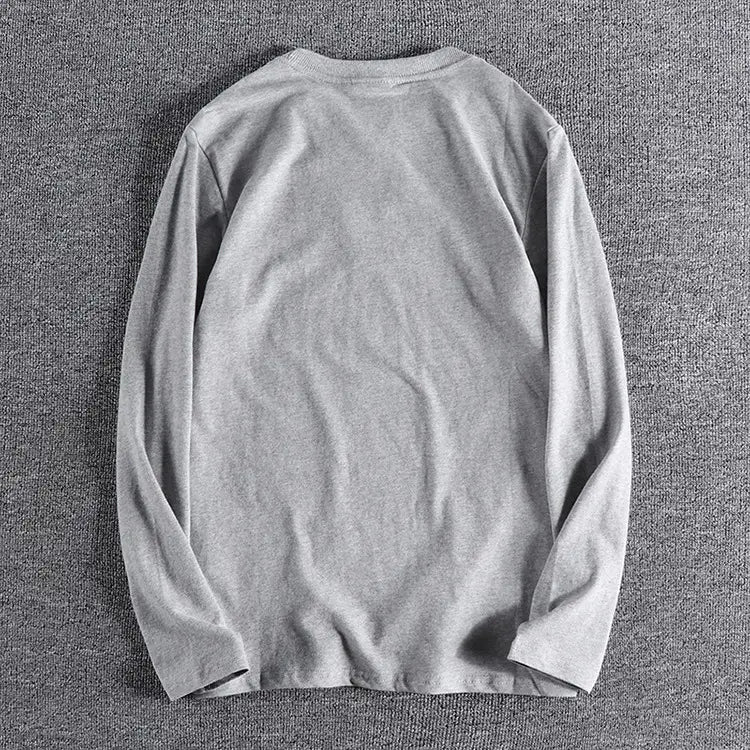 Camiseta tipo jersey de color liso lavado gris de manga larga confeccionada con tejido de algodón suave con diseño de cuello redondo.