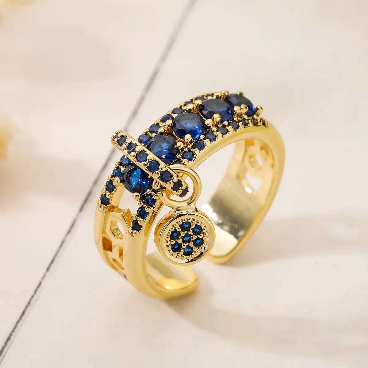 Adjustable geometric gold open ring featuring deep blue zircon charms and a dangling circular charm.
