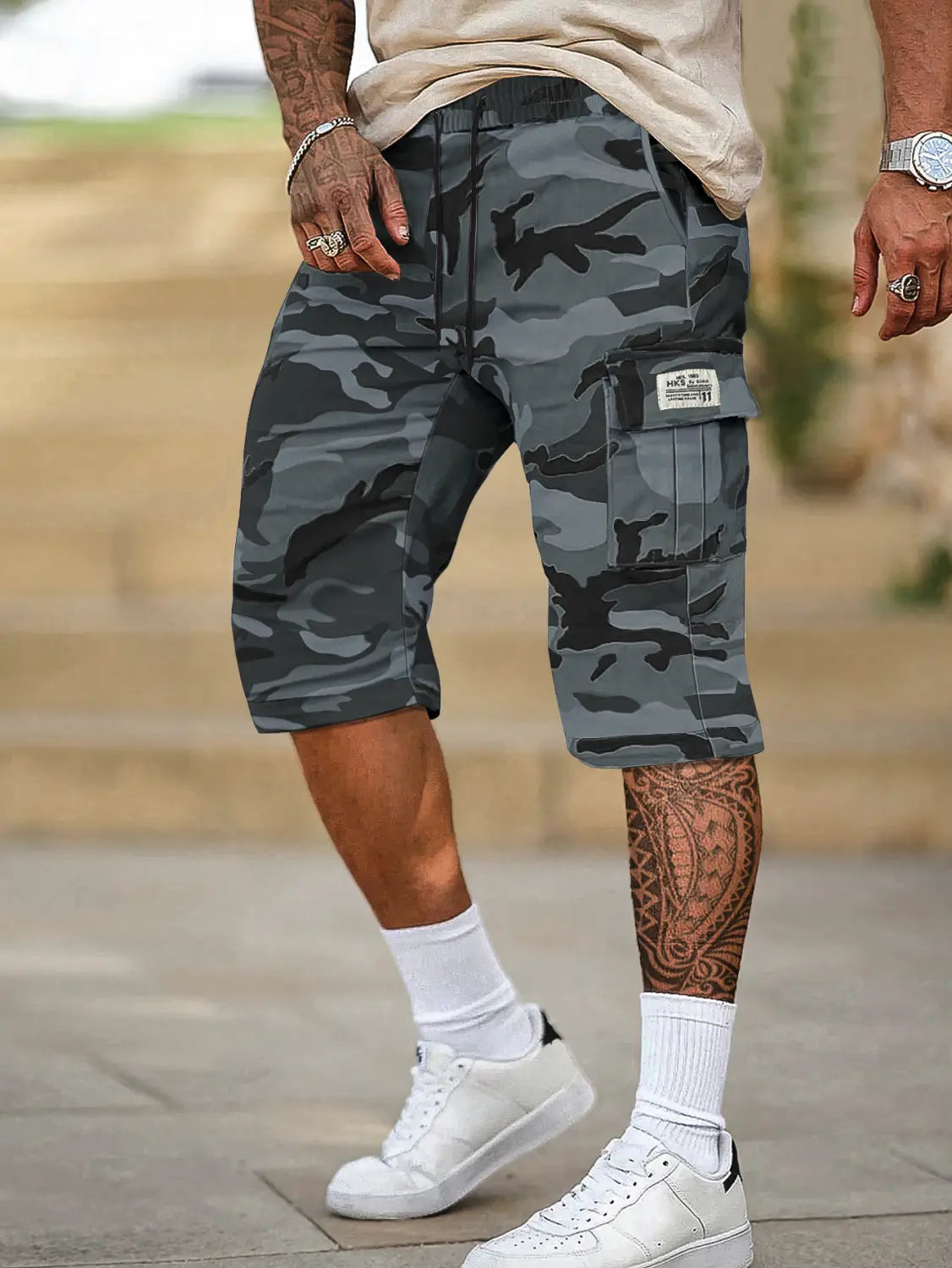 Short cargo camouflage gris et noir pour homme, coupe ample, conception à poches multiples et taille à cordon de serrage.
