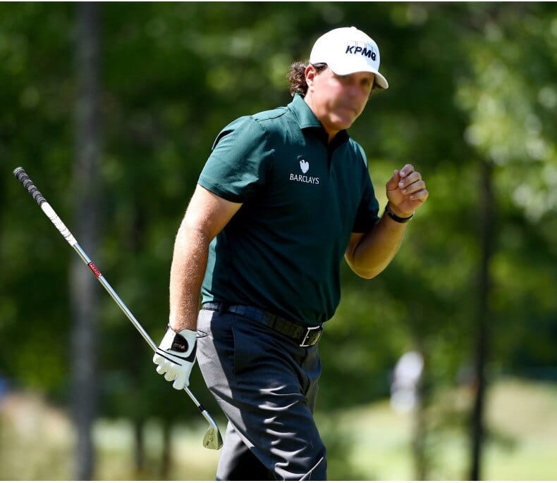 A man wearing a white kpmg cap and dark green barclays polo shirt models a men genuine leather breathable golf glove.