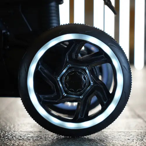 black wheel with a glowing white led ring around the rim on the back side of a 6v kids electric ride on motorcycle red.