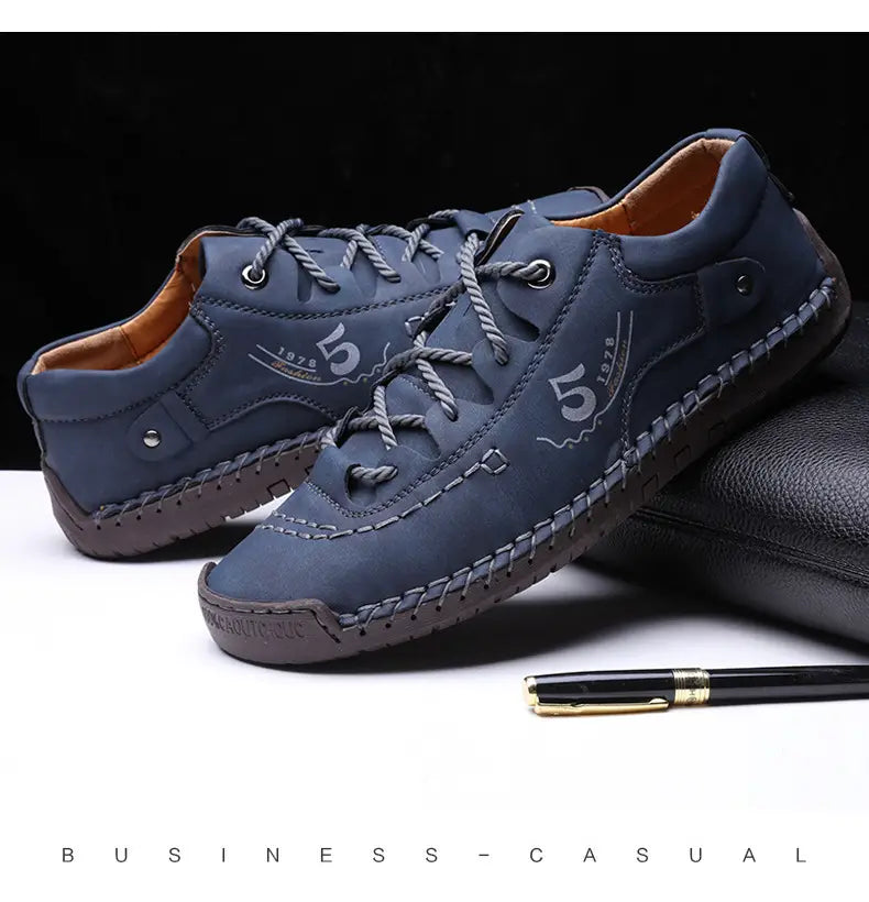 Herren-Lederschuhe im britischen Casual-Stil mit Schnürung aus dunkelblauem (Marine-)Farbton mit grauen Schnürsenkeln und gestickten Details.