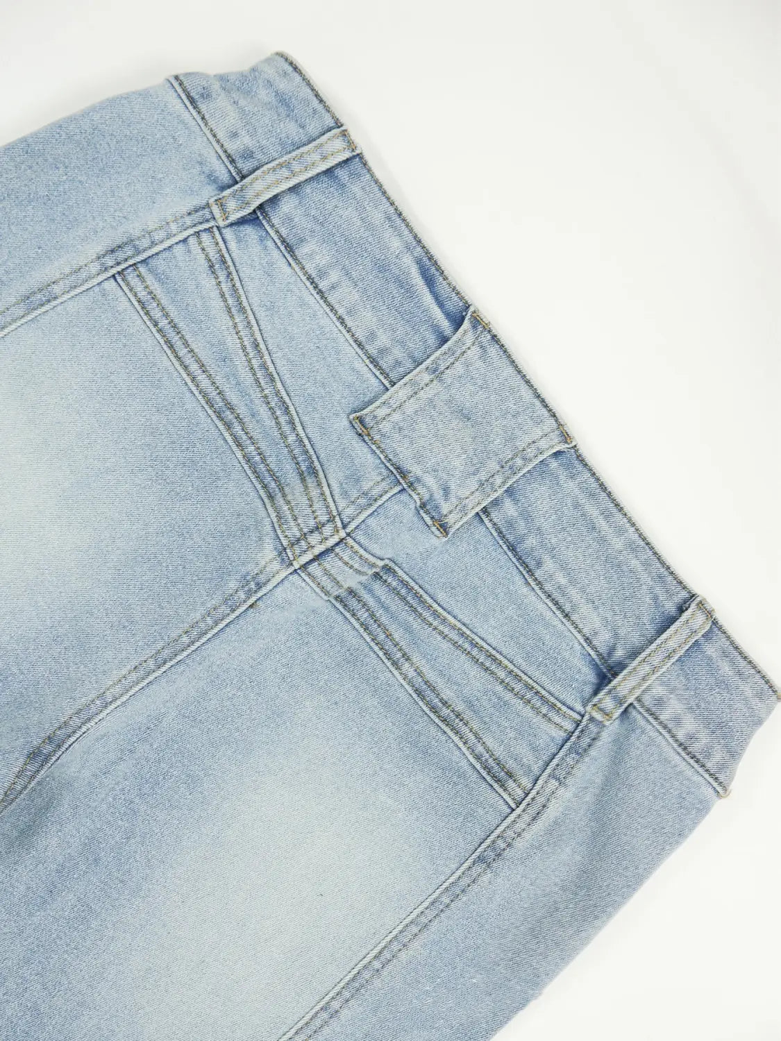 Hell gewaschener Jeansrock mit hoher Taille und sichtbaren Steppdetails, kombiniert mit schwarzen Bootcut-Jeans, die hohe Elastizität und eine schlanke Passform aufweisen.