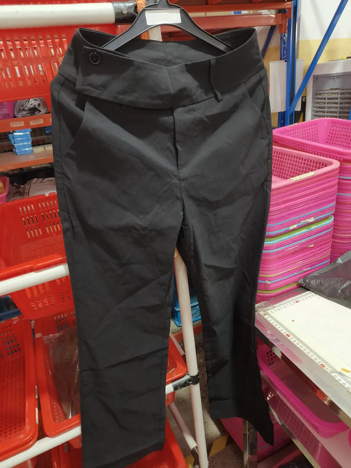 Black tailored wide leg work pants high waist casual trousers with buttoned waistband hanging on a hanger.
