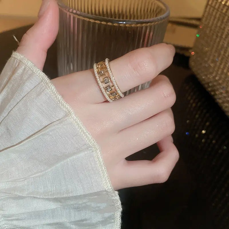 A gold-toned hollowed square pearl and baguette zircon open ring with a wide band featuring embedded square-cut stones and a delicate beaded edge.