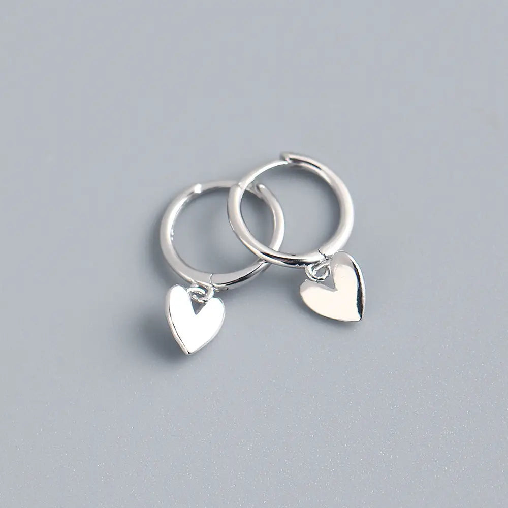 Minimalistische herzförmige Creolen aus Silber mit einem polierten herzförmigen Anhänger-Design mit minimalistischer Ästhetik.