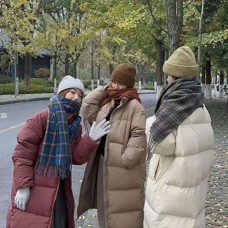 Three women wearing long quilted puffer coats in rust red tan and cream cotton winter jackets designed for cold weather.