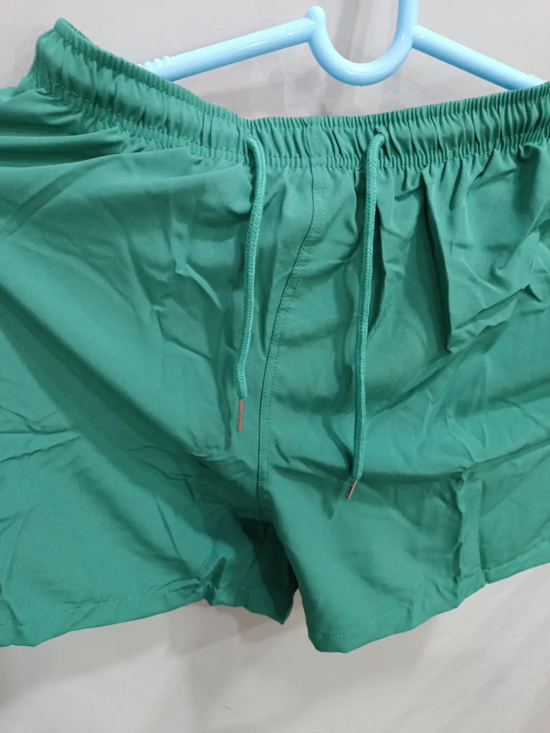 Green swim trunks with elastic waistband and matching drawstrings from printed men beach shorts summer swim trunks collection designed for summer beachwear.