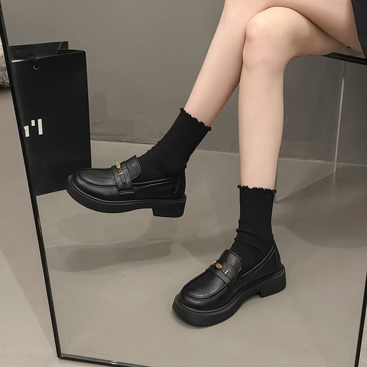 black leather loafers with a gold-tone buckle and chunky sole displayed from the back side