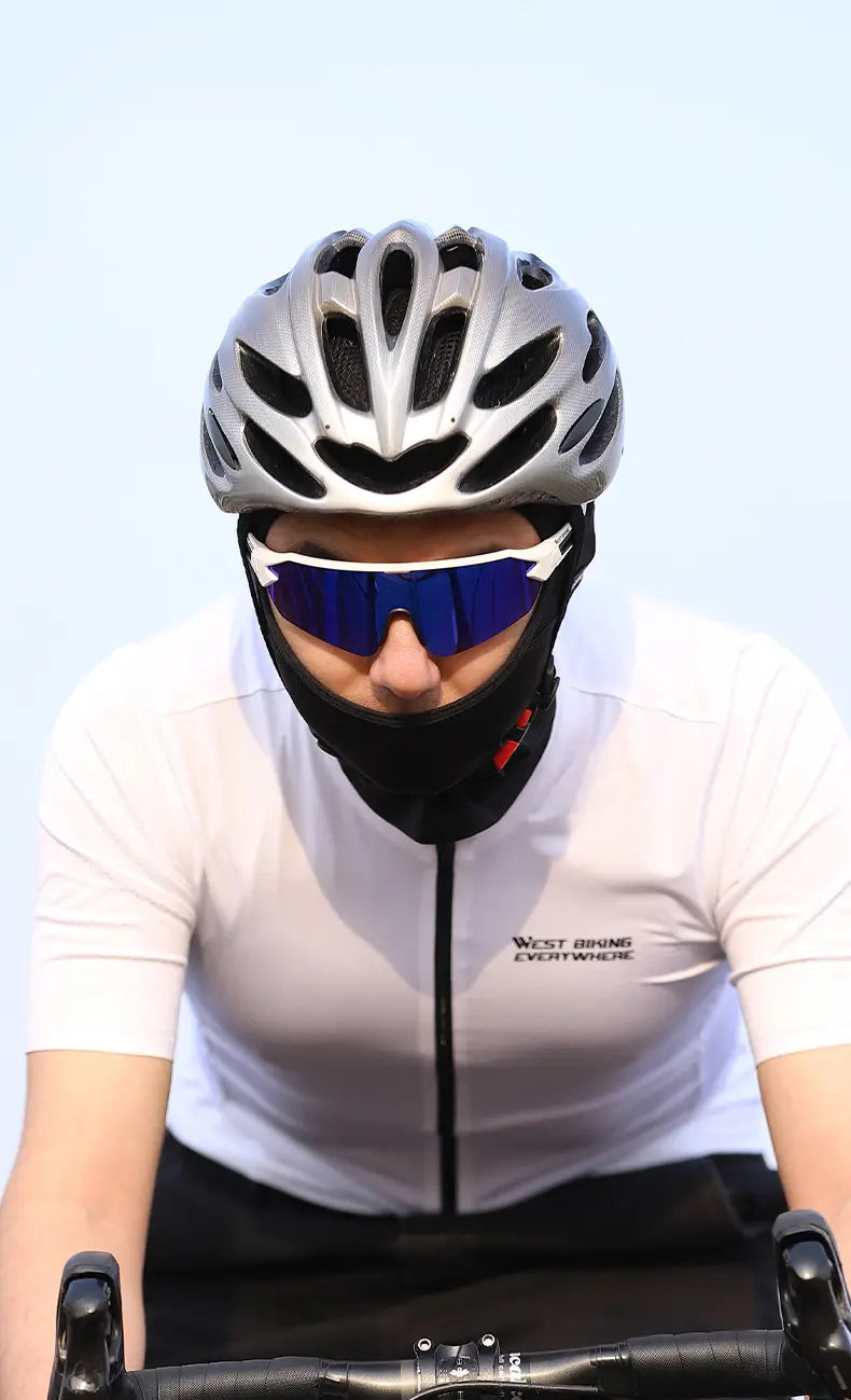 Silver aerodynamic bicycle helmet with black ventilation slots and a matte finish shown alongside a neon green cycling balaclava sun protection mask.
