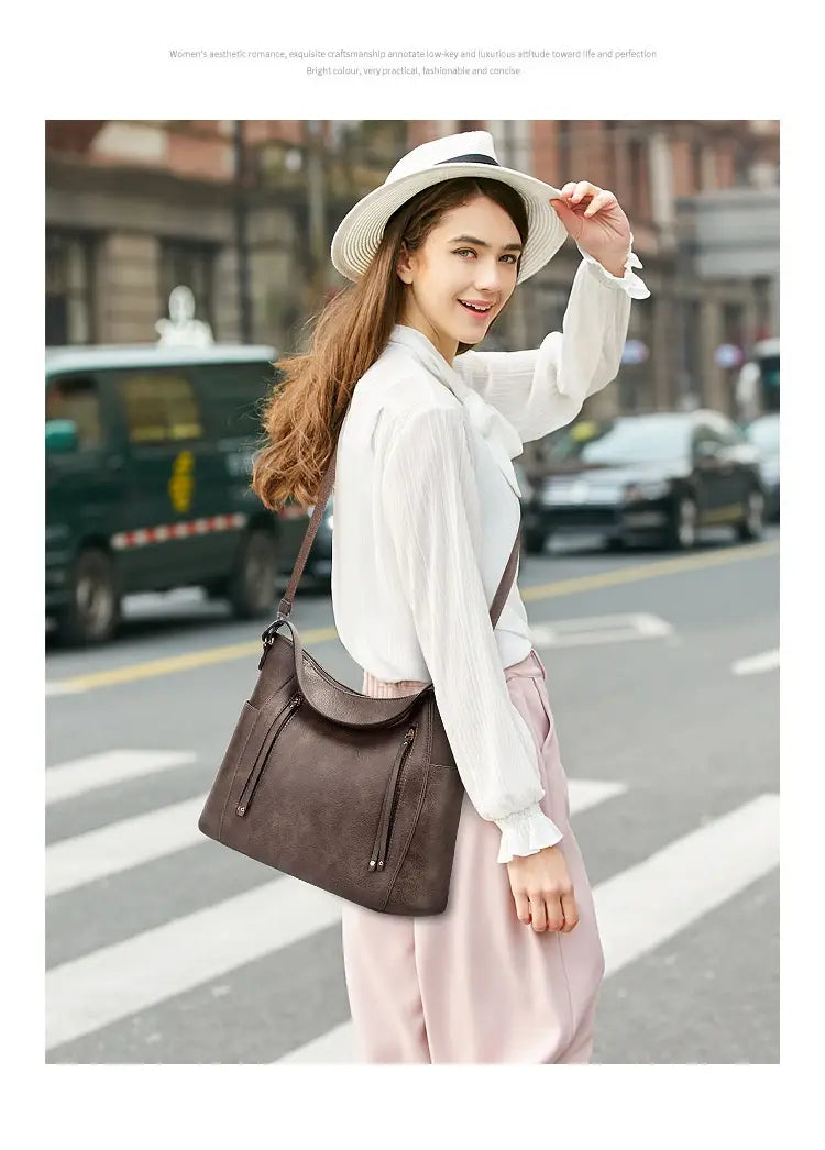 brown leather shoulder bag with curved top, zipper closures, tassel, and front zipper pockets for everyday use
