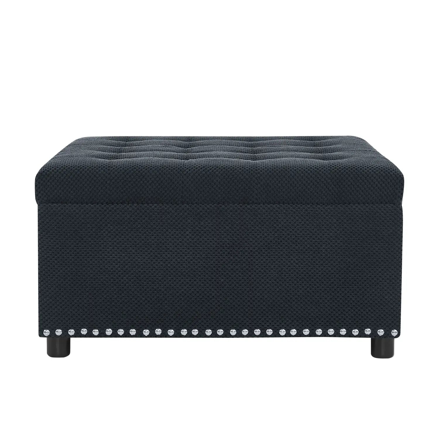 Black tufted storage ottoman in textured fabric finish with silver nailhead trim along the base.