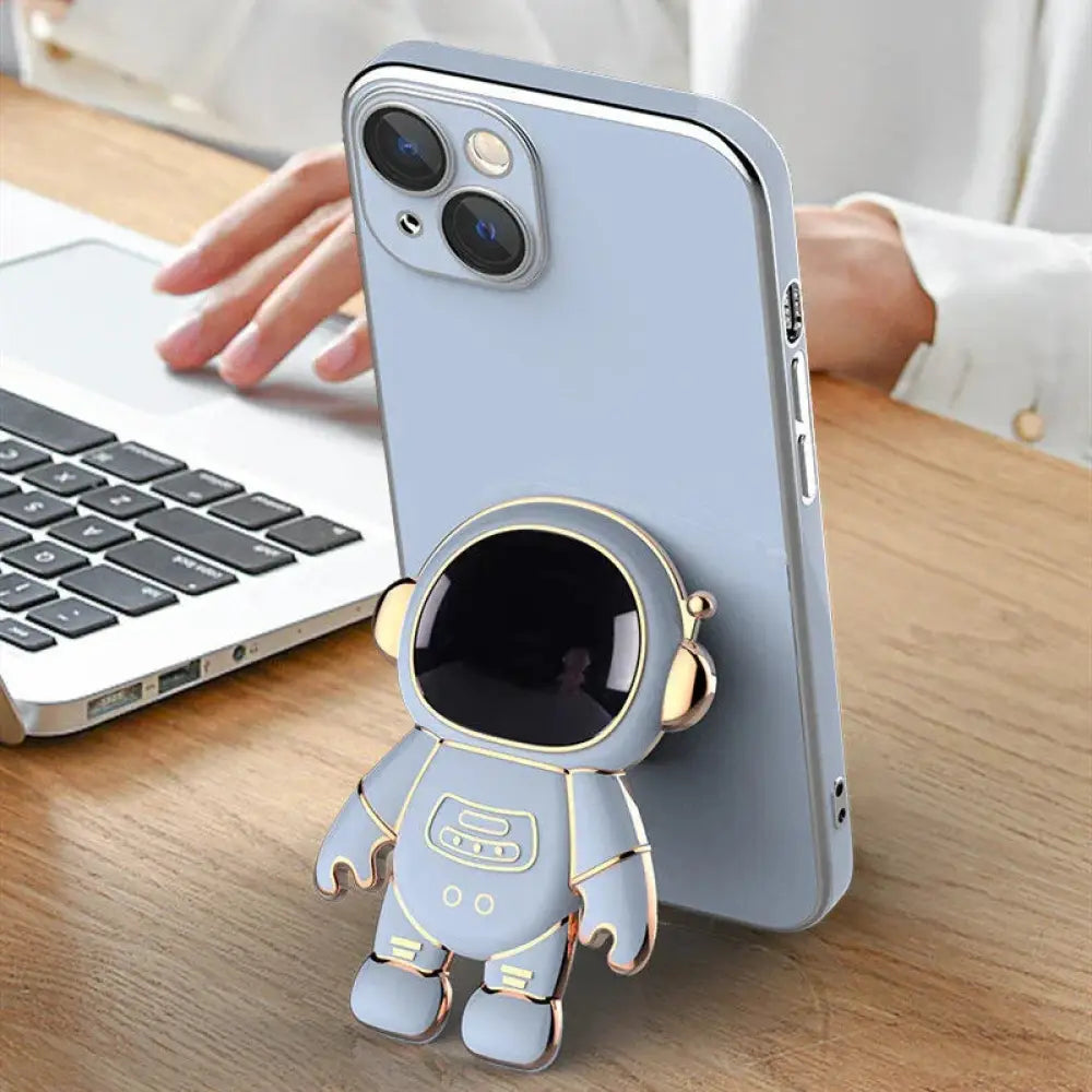 Light blue astronaut-themed electroplated phone stand with gold accents designed to hold a smartphone upright