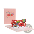 A vibrant red 3d pop up valentine card with glittery love you letters and rainbow hot air balloon design on pink background