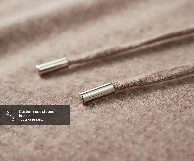 Topes de cuerda metálicos con acabado en tono plateado, de diseño cilíndrico elegante, sujetos a un cordón beige suave en una sudadera con capucha de cachemir para hombre, para un uso de jersey holgado de invierno
