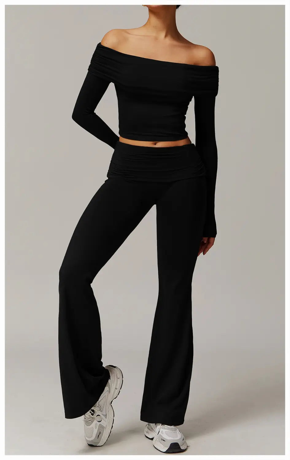 top corto negro acanalado de manga larga estilo hombro descubierto, combinado con pantalones de yoga acampanados negros de cintura alta y zapatillas blancas chunky para un look athleisure con estilo