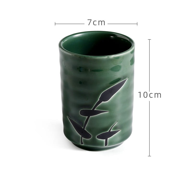 A matte green Japanese ceramic mug with a subtle textured surface and black leaf decals designed as a retro hand-painted tea cup 250ml.
