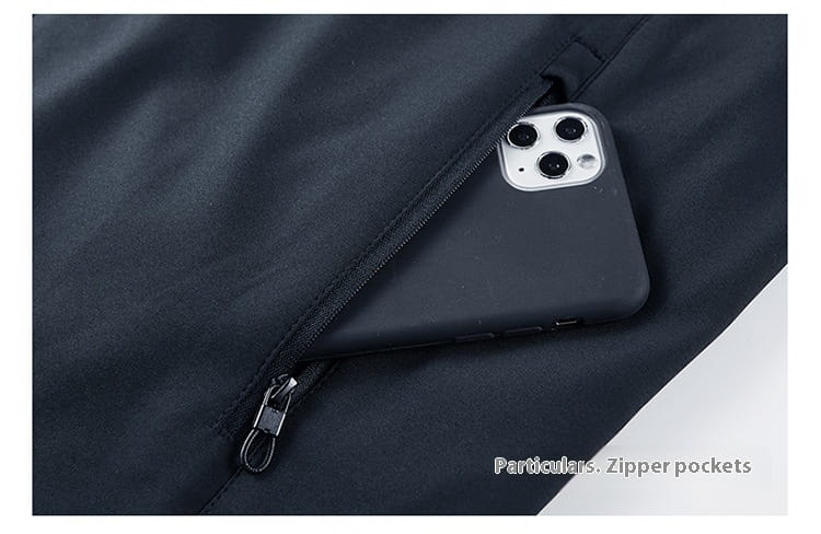 a black smartphone with a matte finish rests inside the dark navy zipper pocket of a men casual jacket lightweight outdoor windbreaker made from breathable material for versatile use.