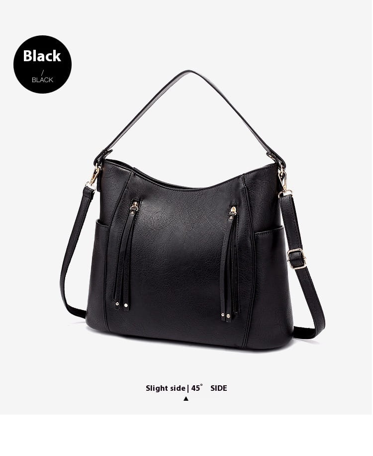 Black faux leather leather hobo bag with tassel details and front zipper pockets featuring an adjustable shoulder strap.