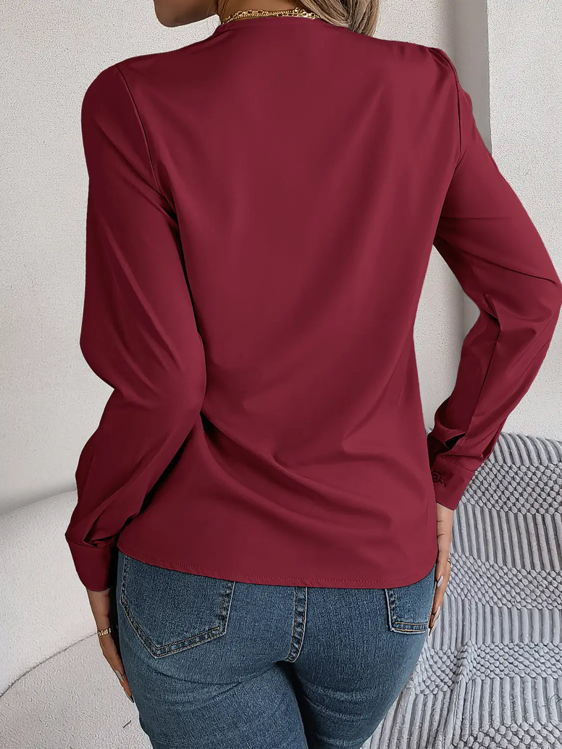 A sleek long-sleeved maroon satin blouse with subtle shoulder detailing and black trim designed as a white satin v neck wrap blouse.
