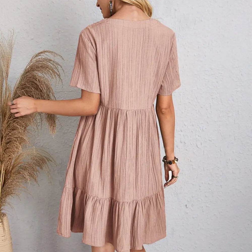 Une robe d’été souple rose en coton côtelé pour femmes, à encolure en V, à volants superposés, à manches courtes et avec des volants superposés.