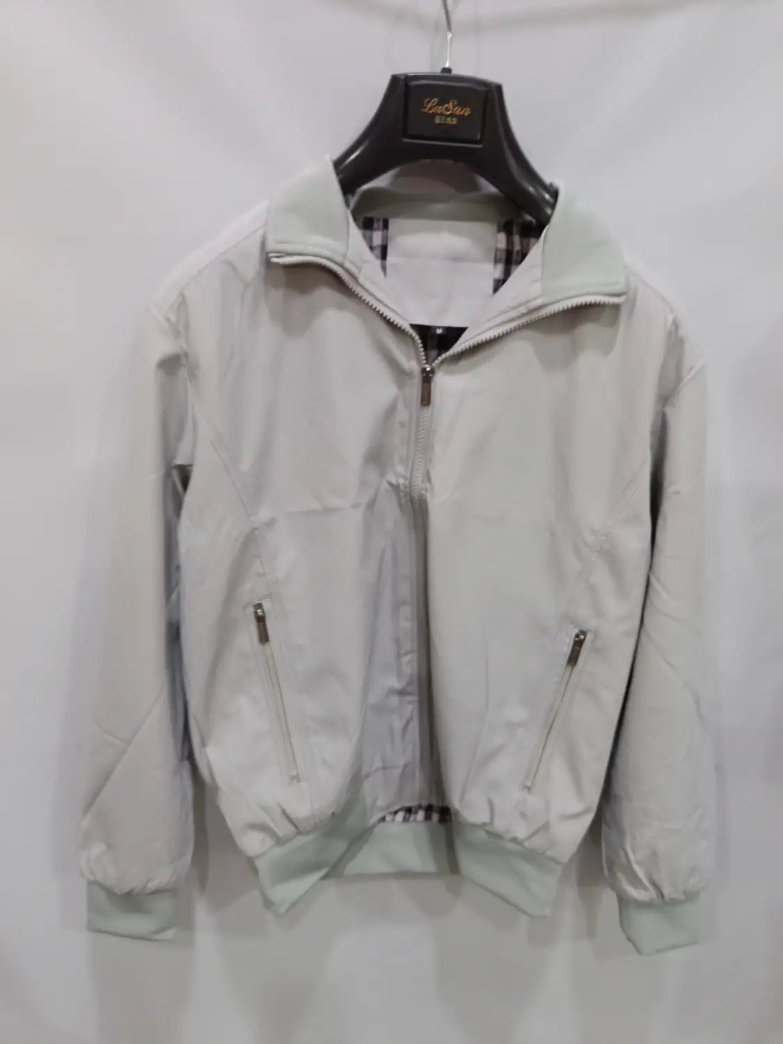 Veste bombardier légère pour homme en gris clair, avec fermeture à glissière, poignets et bas côtelés, deux poches avant zippées et doublure à carreaux.