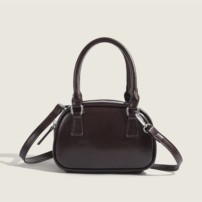 Dark brown leather mini handbag with curved top handles and a detachable shoulder strap made of glossy pu leather in a small square design measuring 20cm.
