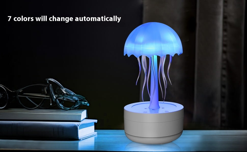Blue glowing jellyfish-shaped led lamp with translucent dome and flowing tentacles resting on a white cylindrical base for the jellyfish humidifier 7 color led essential oil diffuser.